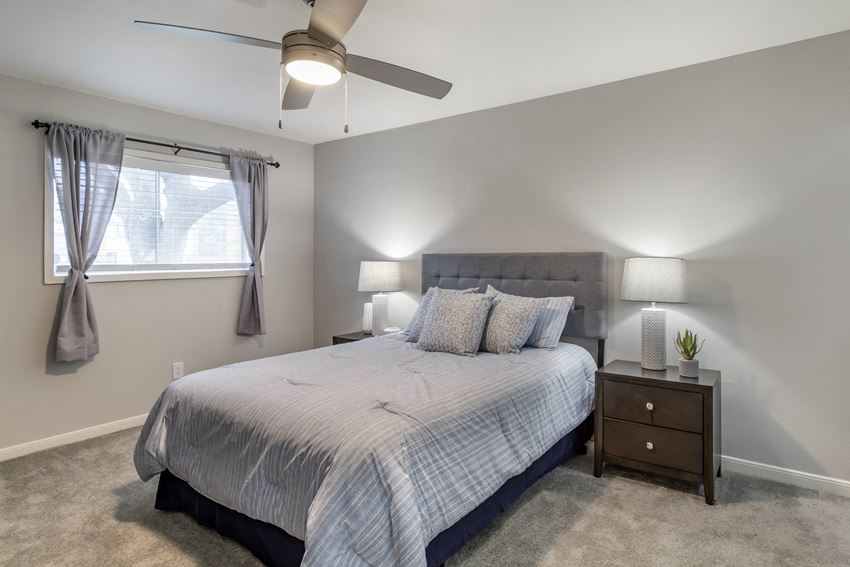an empty bedroom with a bed and a ceiling fan
