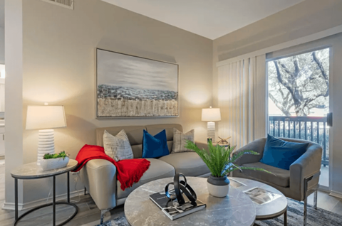 A living room with a grey couch, a coffee table, and a painting on the wall.