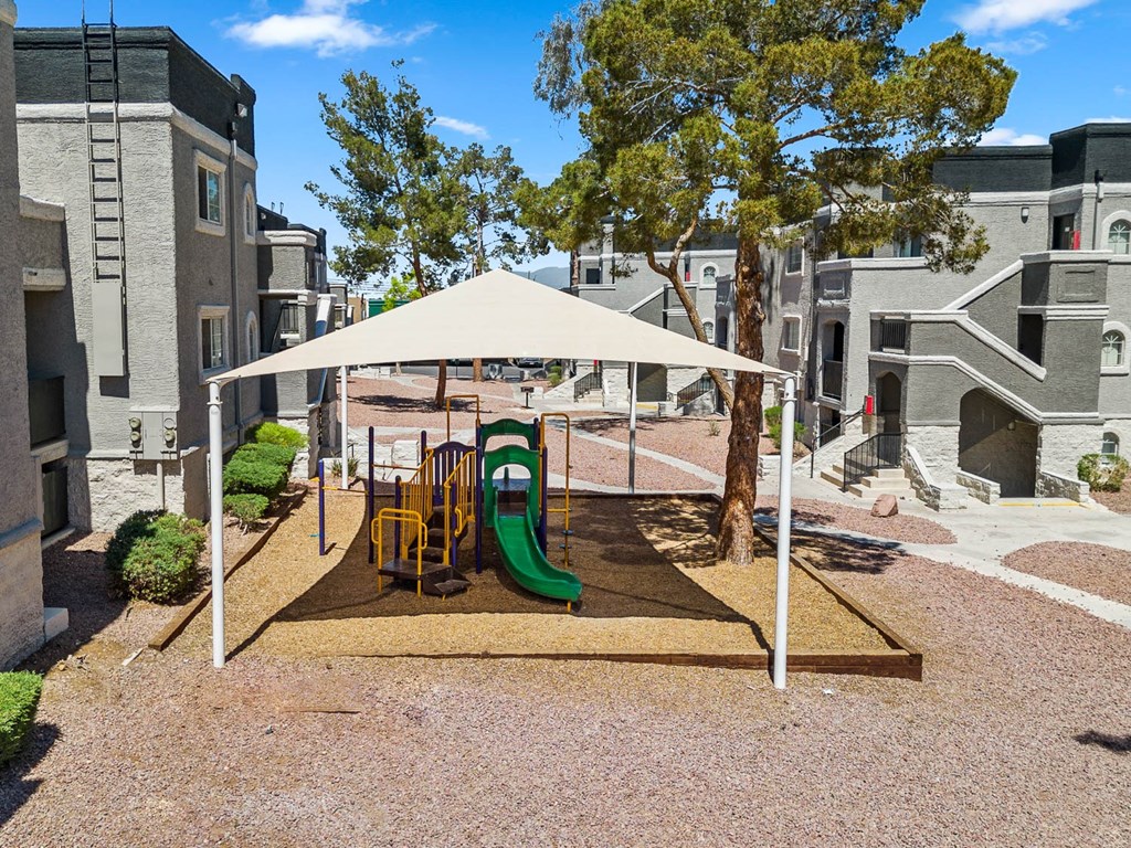 a playground with a canopy and slides at the whispering winds apartments in pearland, tx