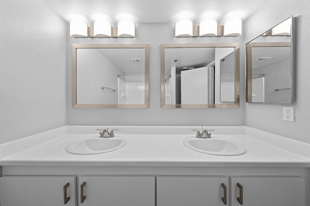 a bathroom with two sinks and three mirrors