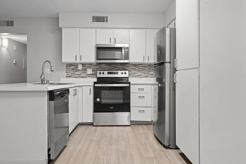 a kitchen with white cabinets and stainless steel appliances