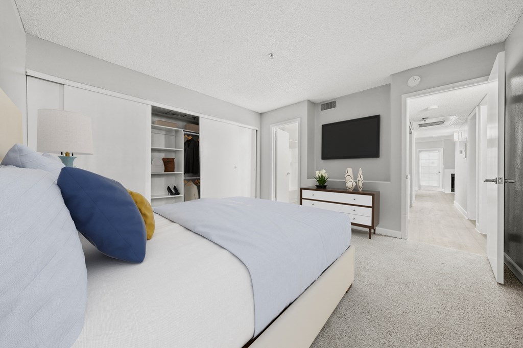 a bedroom with a bed and a dresser with a television on the wall