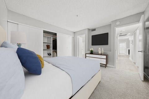 a bedroom with a bed and a dresser with a television on the wall