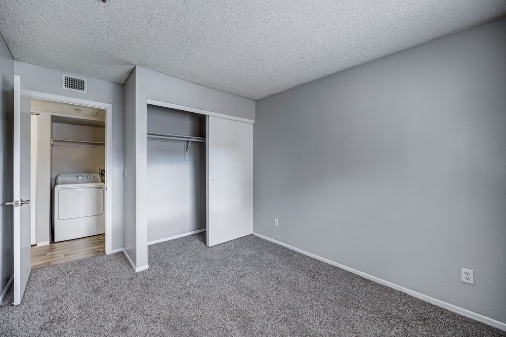 the living room of an apartment with an open door to the kitchen and laundry closet