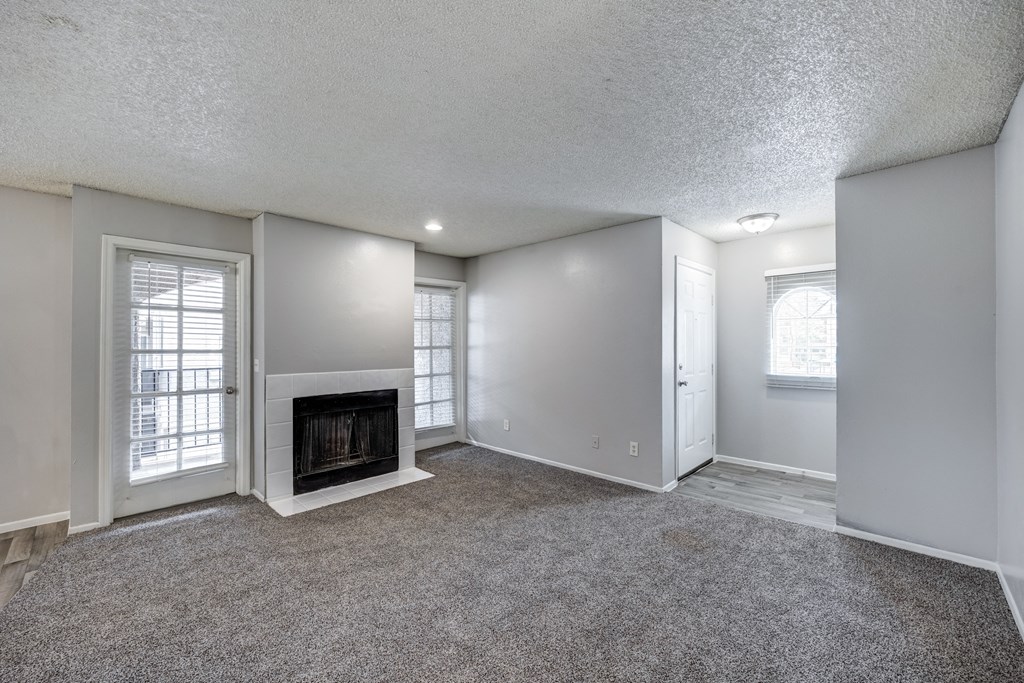 an empty living room with a fireplace and windows