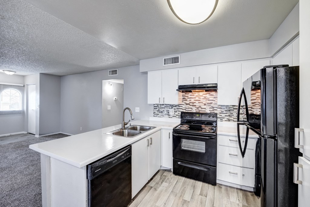 an empty kitchen with white cabinets and black appliances