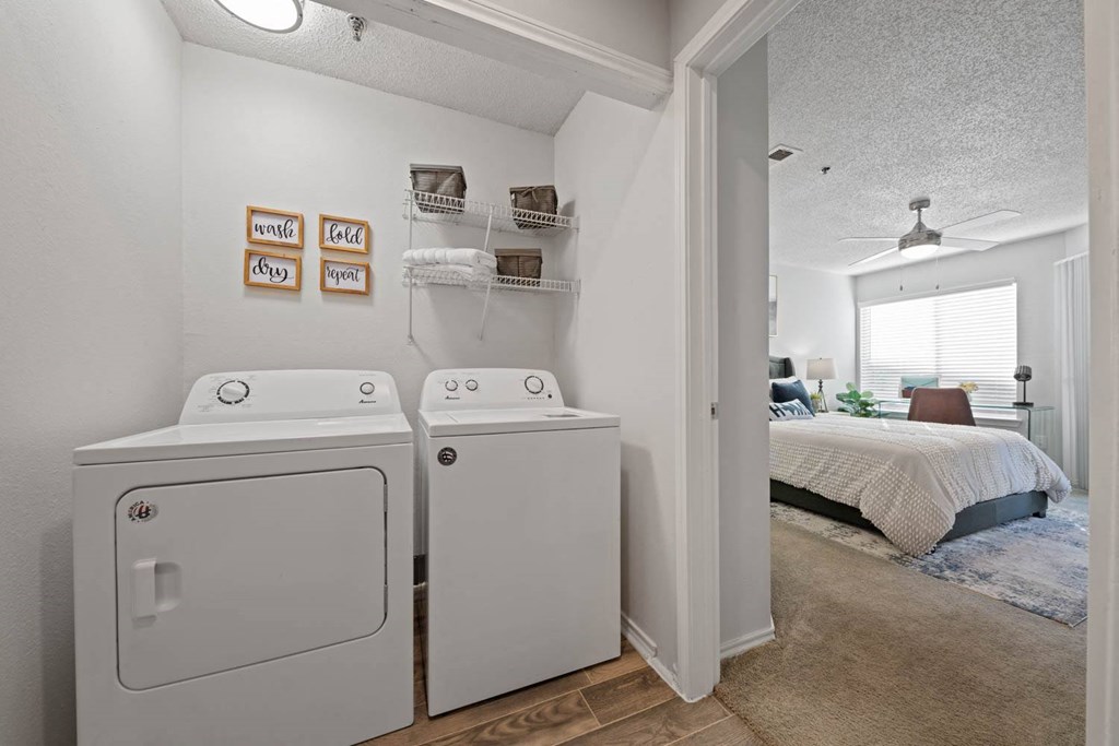 a washer and dryer in a bedroom with a bed