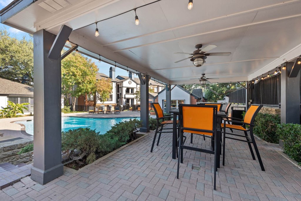 a patio with a table and chairs next to a pool