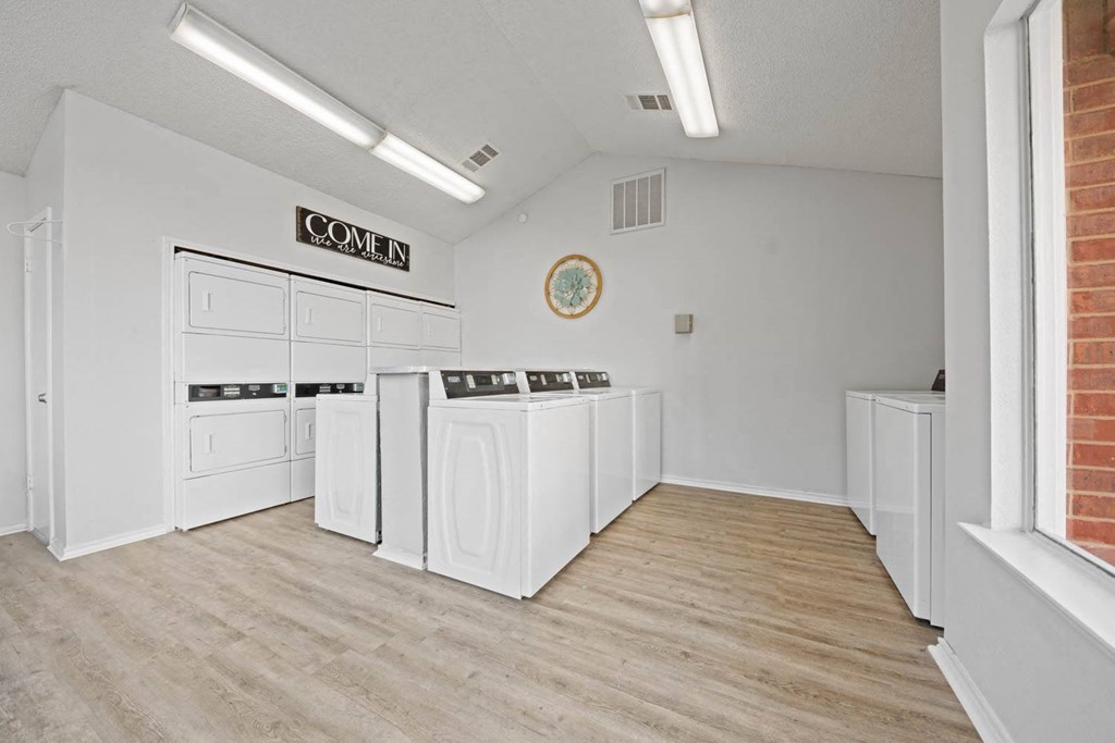a laundry room with washers and dryers and a sign