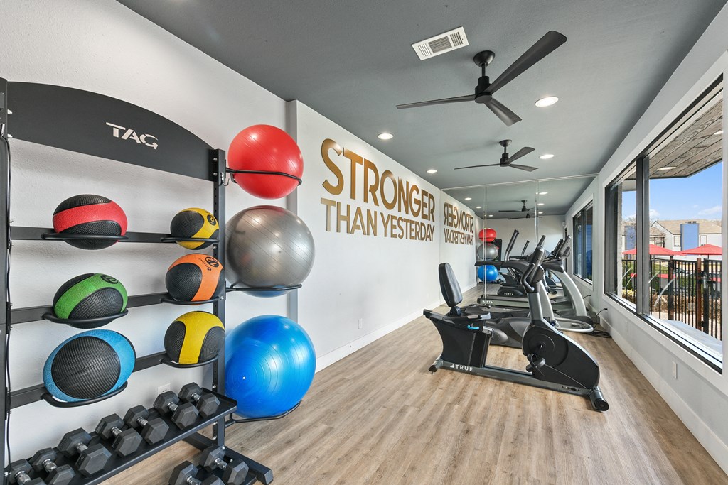 a gym with weights and exercise equipment and a wall with a sign that reads stronger