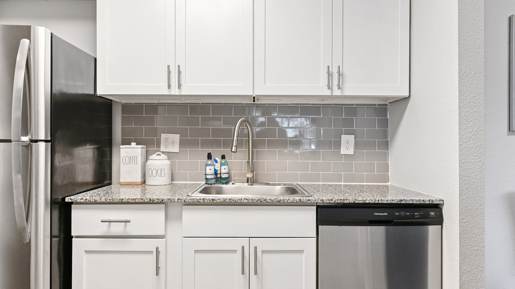 a kitchen with white cabinets and a sink and a refrigerator