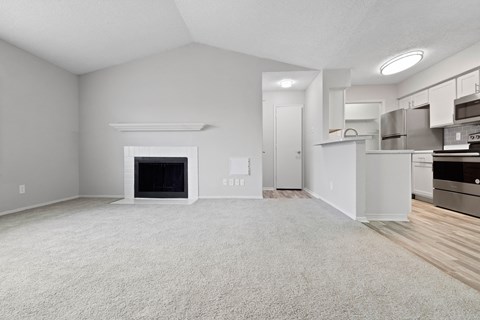 a living room with a fireplace and a kitchen in the background