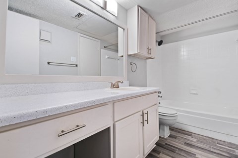 a bathroom with white cabinetry and a white toilet next to a white bathtub
