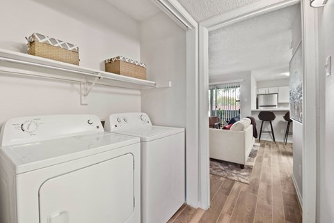 a washer and dryer in a room with a living room and kitchen in the background