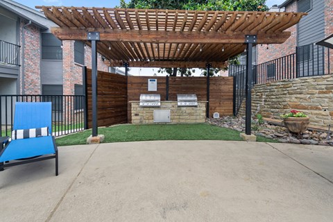 a patio with a pergola and a grill