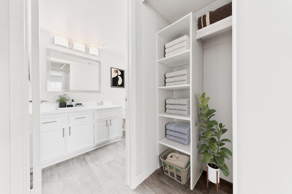 a white bathroom with a large closet with towels and a sink
