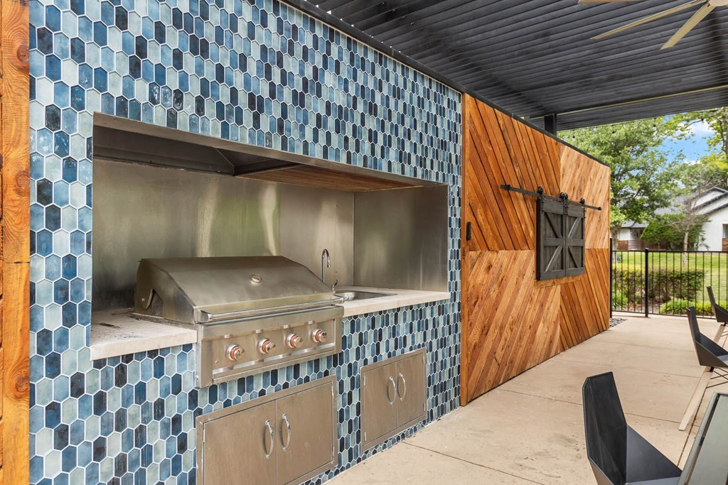 an outdoor kitchen with a grill and a wooden door