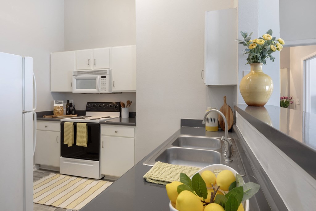 a kitchen with white appliances and a counter with a bowl of fruit