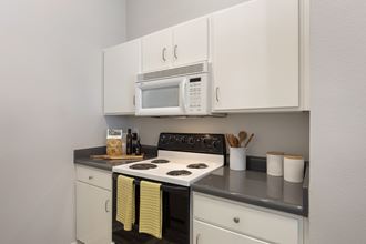 a kitchen with white cabinets and a stove and a microwave