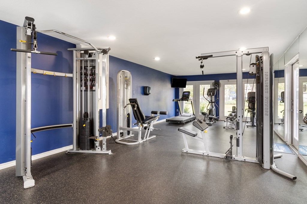 a gym with weights and cardio equipment and blue walls
