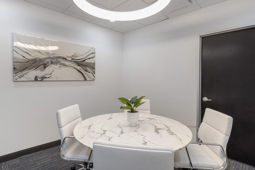 a small meeting room with a round table and white chairs