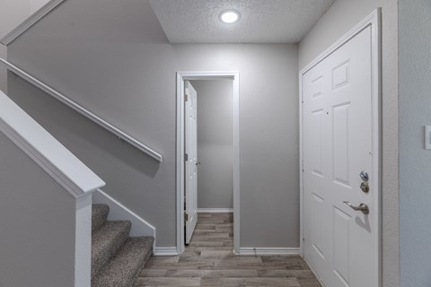 A hallway with a staircase and a door.