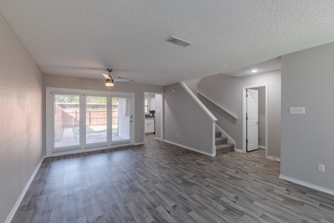 A spacious room with a staircase and sliding glass doors.