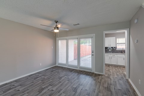 A room with a ceiling fan and sliding glass doors.