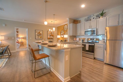 A kitchen with a white refrigerator, a bar area with a marble counter, and a dining area with a table and chairs.