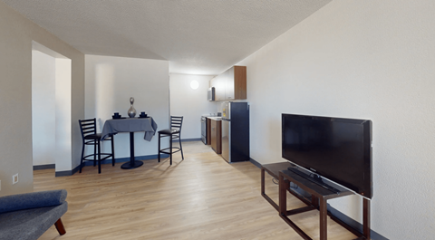 A living room with a grey sofa, a black table, a black television and a black chair.