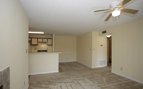 A room with a ceiling fan and carpeted floor.