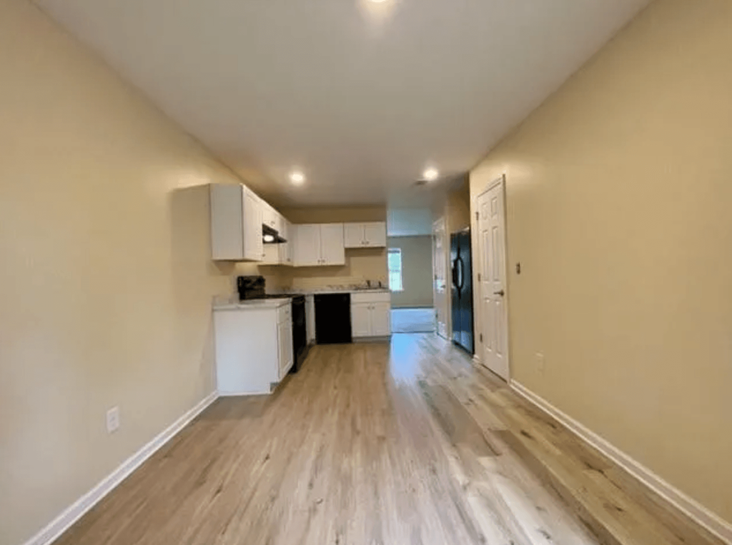 an empty living room and kitchen with wood floors
