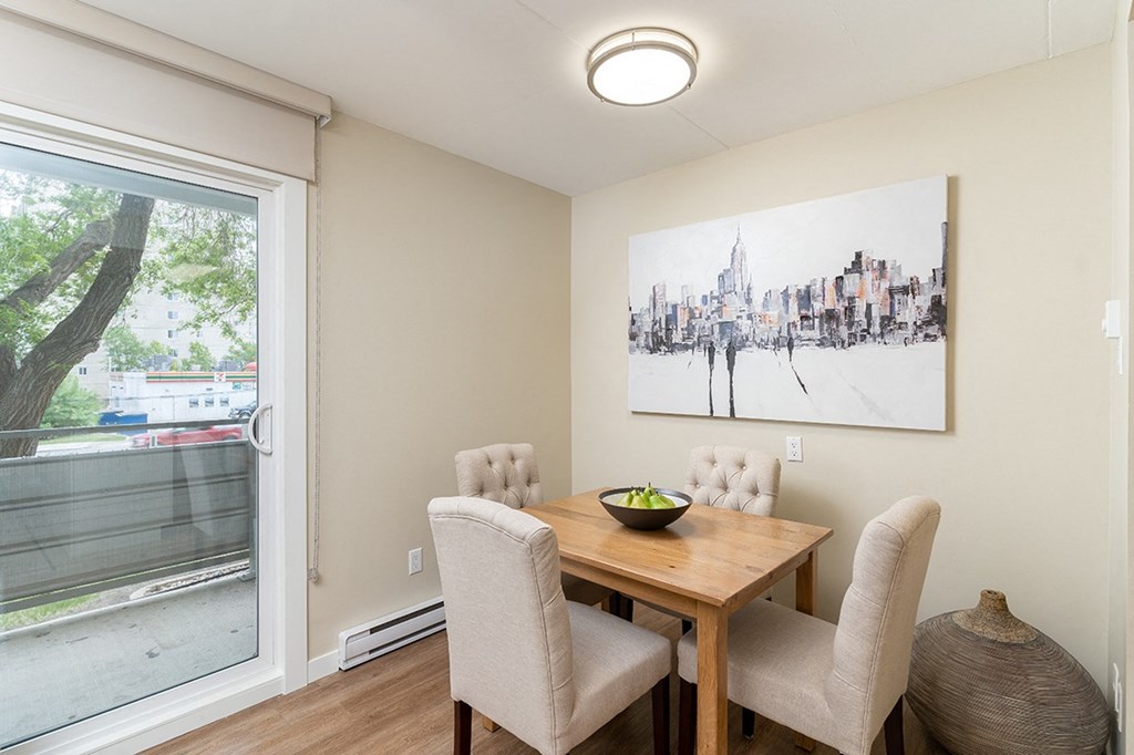 a dining room with a wooden table and chairs and a large painting on the wall