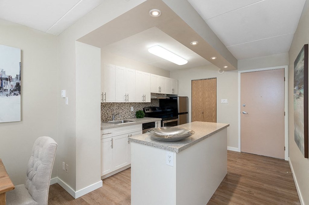 a kitchen with white cabinetry and an island with a granite countertop