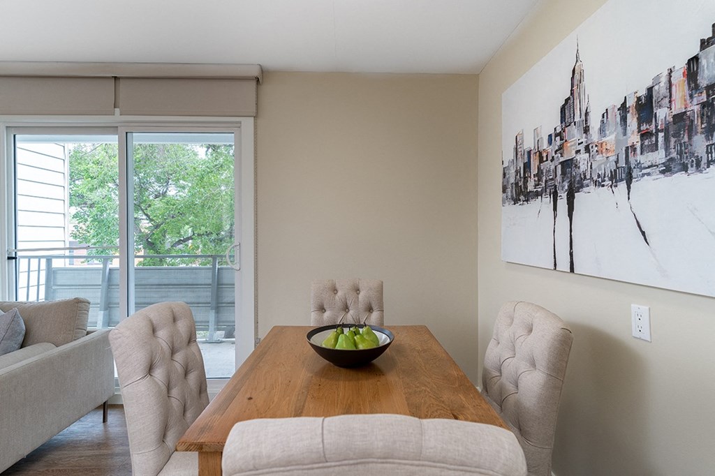 a dining area with a wooden table and chairs and a large painting on the wall