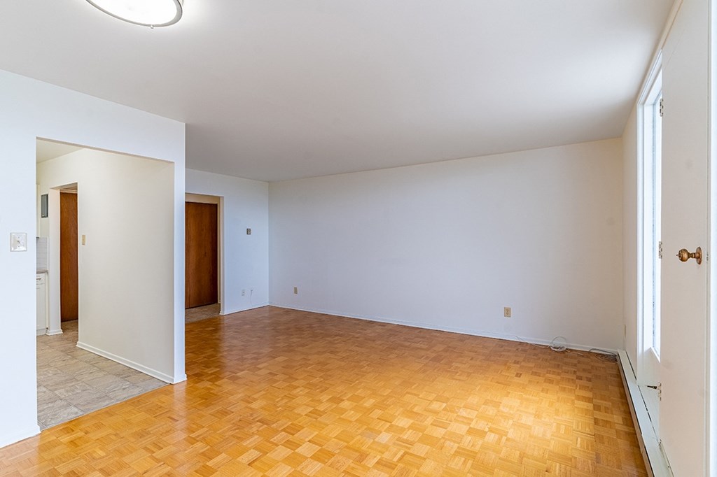 a bedroom with white walls and a wooden floor