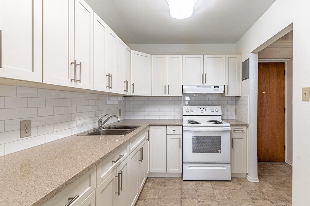 a kitchen with white cabinets and a white stove top oven