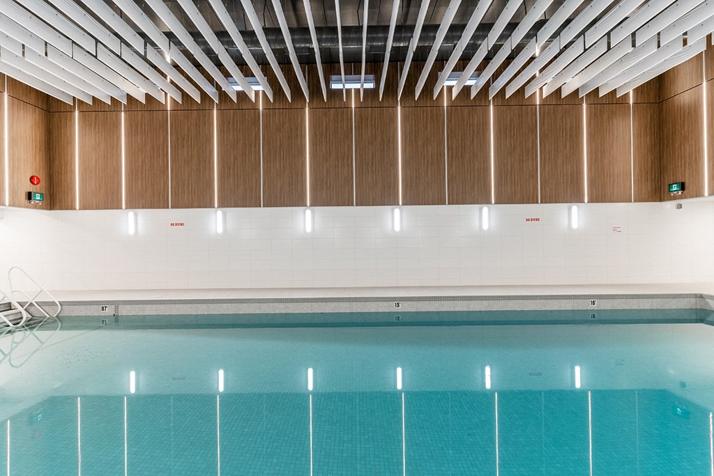 a swimming pool in a building with wooden walls and a ceiling