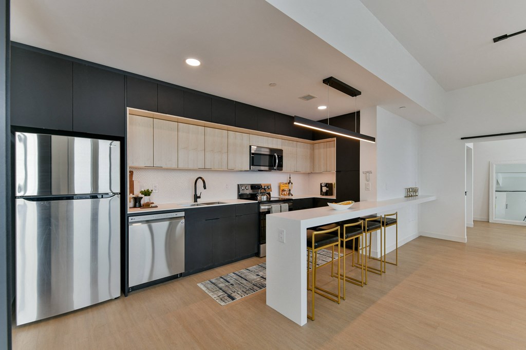 a kitchen with a white island and black cabinets and a stainless steel refrigerator