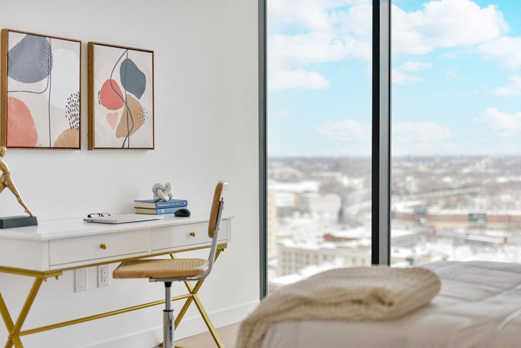 a bedroom with a desk and a window with a city view