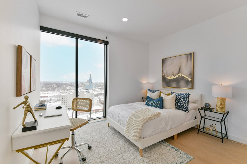 a bedroom with a bed and a desk and a large window