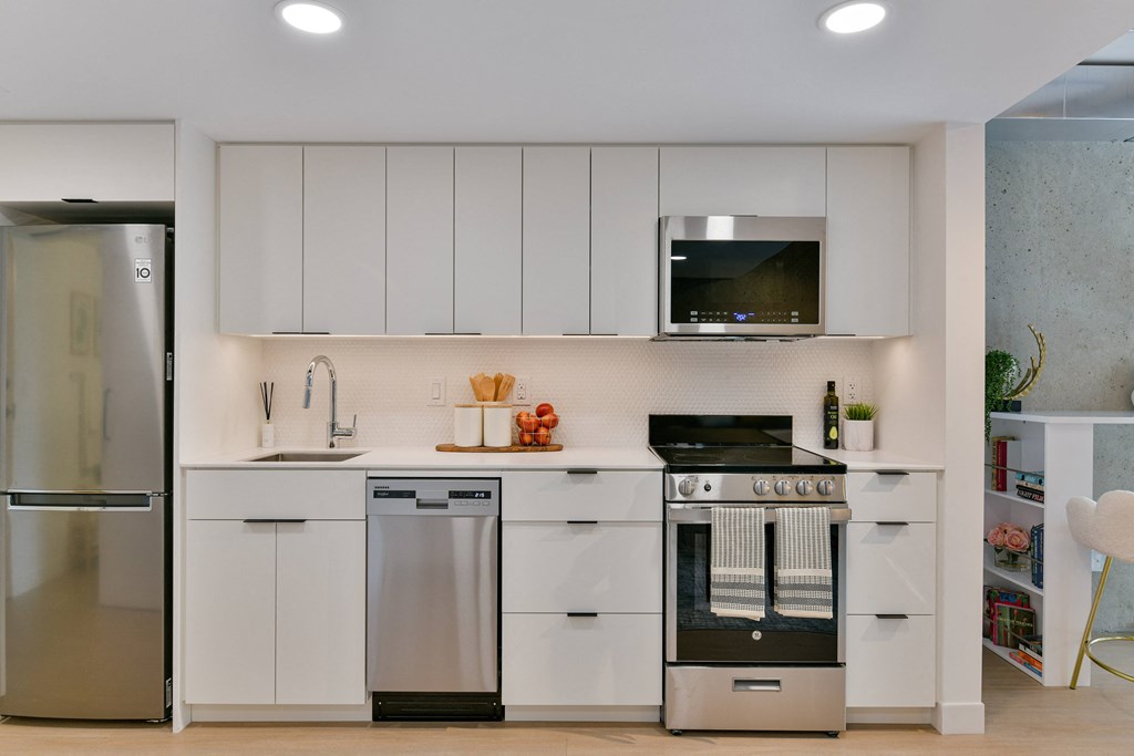 a white kitchen with stainless steel appliances and white cabinets