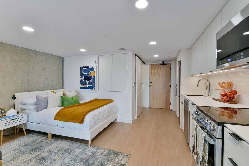 a bedroom with a bed and a kitchen with a stove and a sink