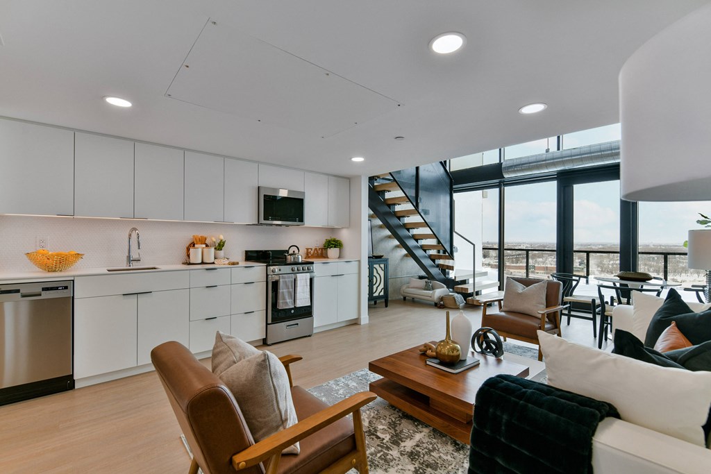 a large living room with a kitchen and a staircase