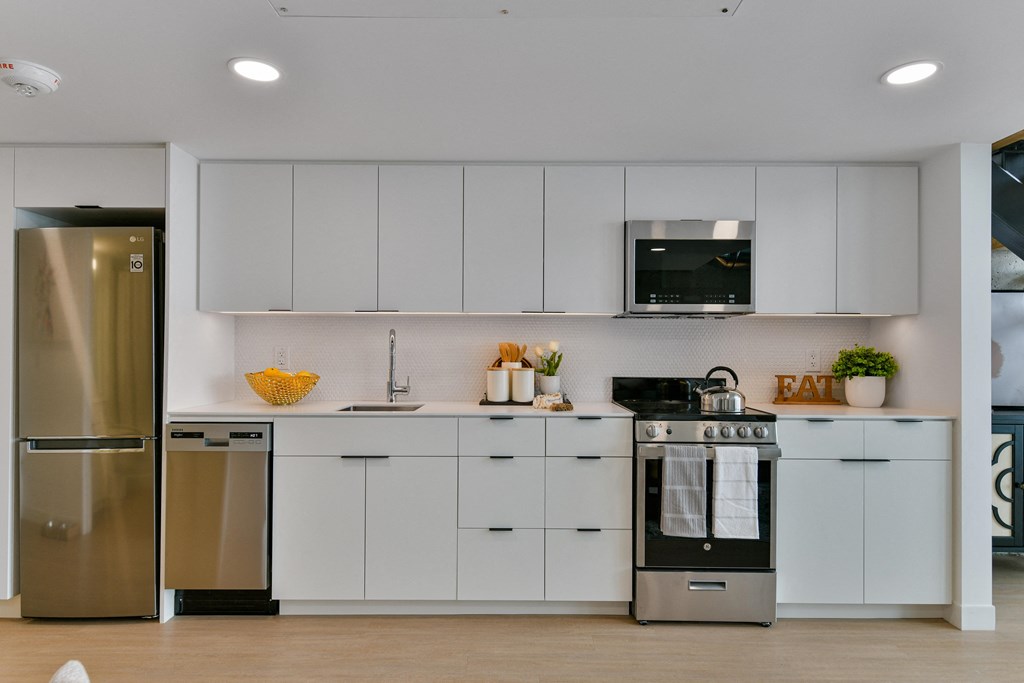 a white kitchen with stainless steel appliances and white cabinets