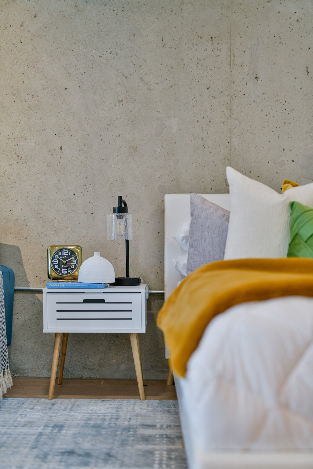 a bedroom with a bed and a night stand with a clock on it