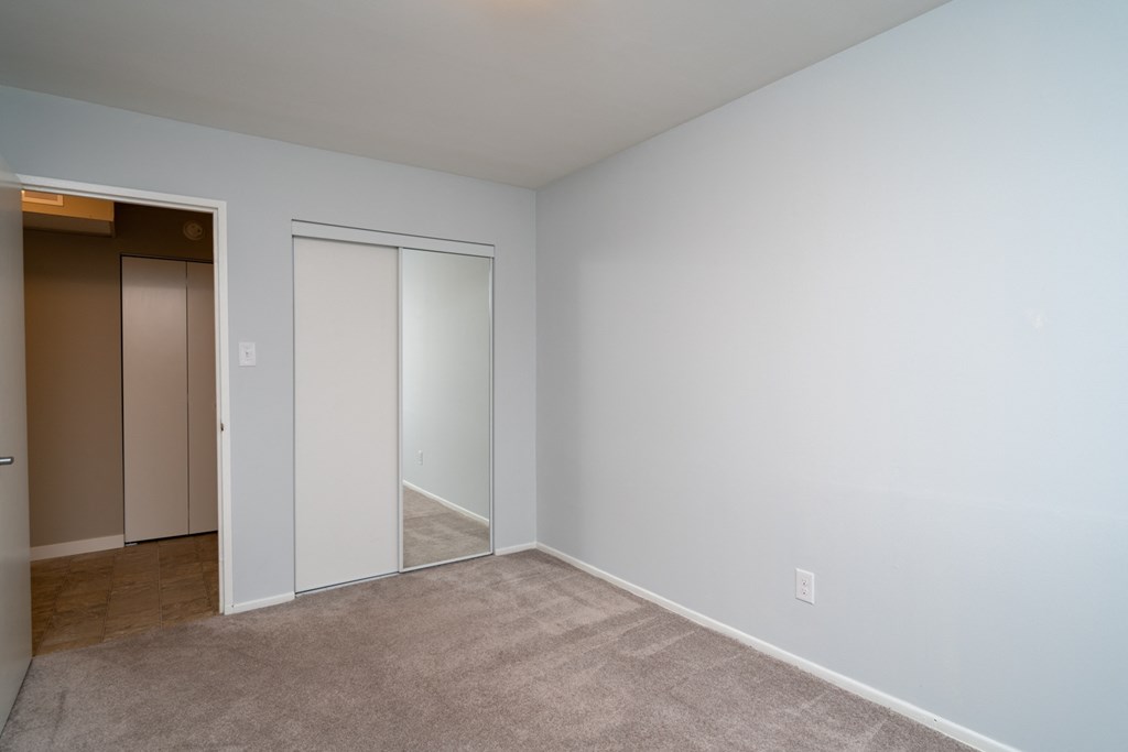 a bedroom with white walls and a beige carpet