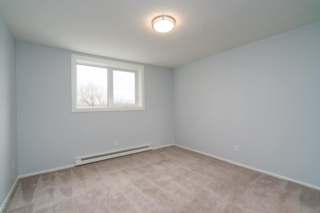 an empty room with a window and a carpeted floor