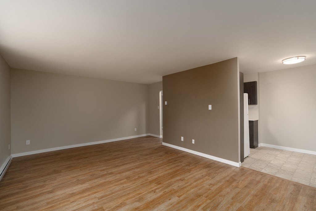 an empty living room with a hardwood floor and grey walls