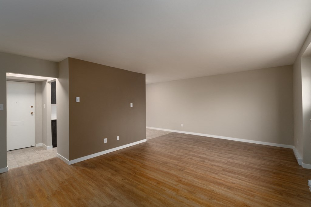 an empty living room with a hardwood floor and grey walls